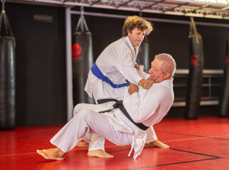 Karate with two male athletes practicing, training and sparring in fight class