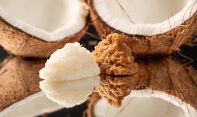 Coconuts and cocadas placed on a reflective surface, black background, selective focus.