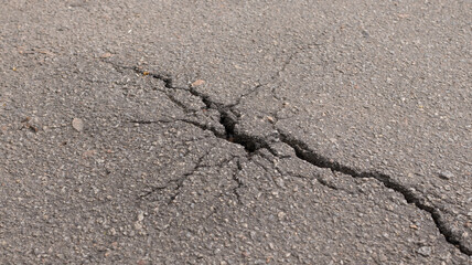 Cracks reveal the hidden story of a weathered asphalt road after years of wear and tear in a quiet...