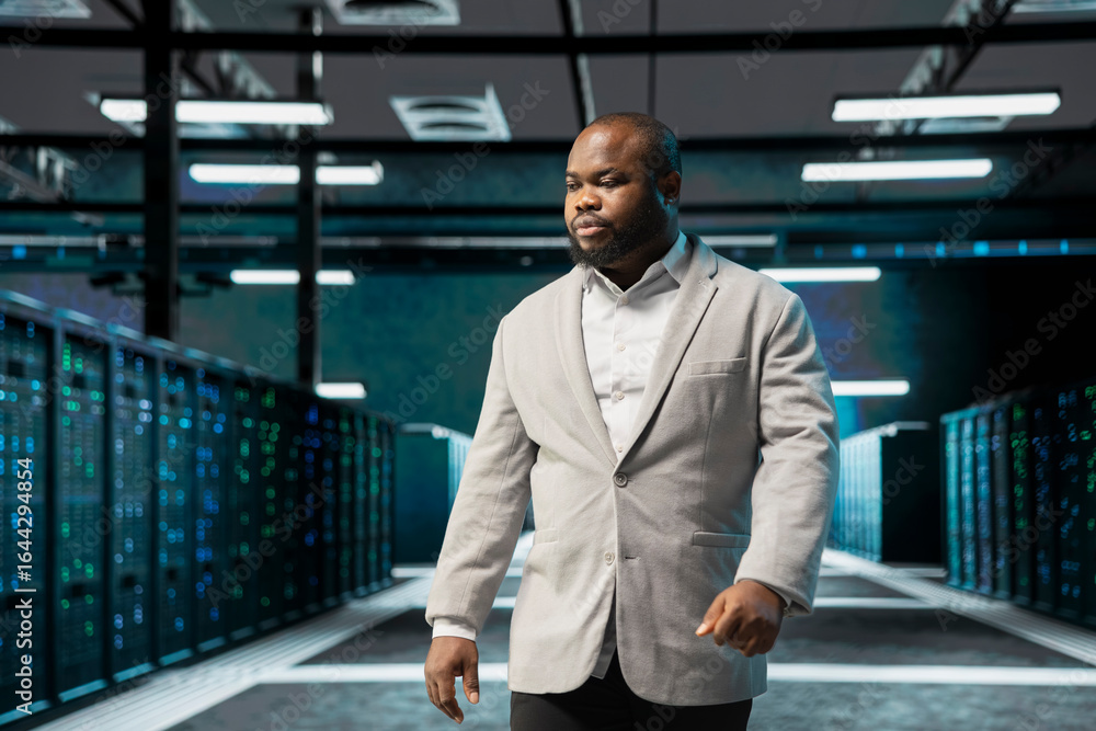 Poster admin walking in server farm, overseeing infrastructure racks used for managing databases. it profes
