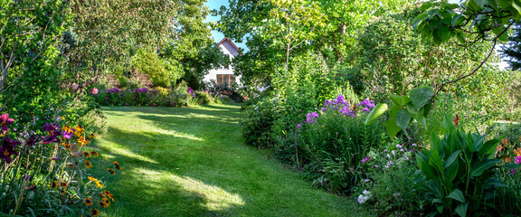 Beautiful garden landscape with fresh green lawn, trees and flowers.