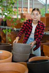 Portrait of a young European woman choosing flower pots for indoor plants at the gardening market