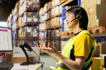 Asian employee answering calls from clients in a distribution hub, handling mix up problems and...
