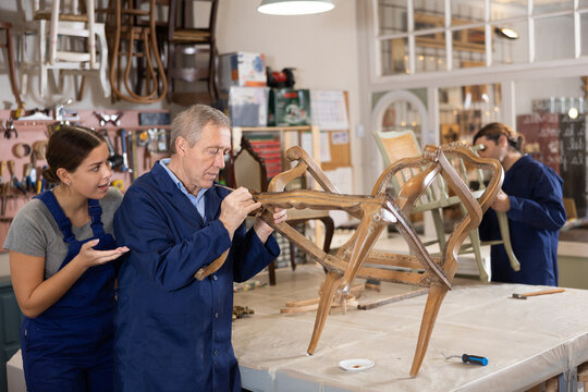 Mature male furniture worker and female apprentice making vintage commode