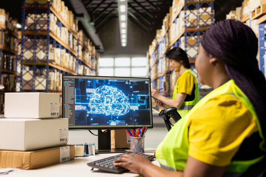 African American female in hi vis vest using AI generated tracking software, helping online shopping orders with artificial intelligence system. Monitoring the parcel status near storage racks.