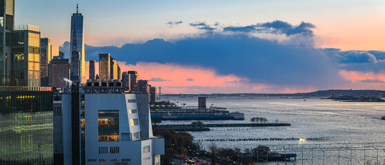 New York City downtown skyline at a dramatic sunset over the Hudson River, USA