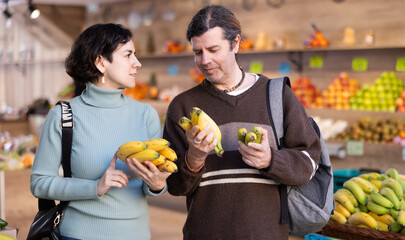 Married couple chooses bananas and other fruits at a supermarket counter