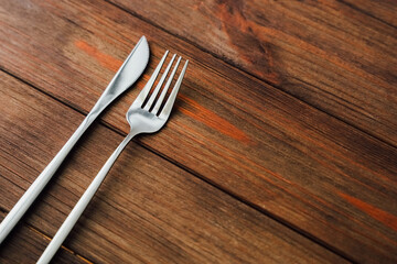 Silver cutlery rests on rustic wooden surface in a dining setting awaiting a meal