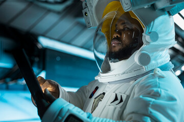 Close up of astronaut scientist operating spacecraft control interface using tablet. Researcher wearing cosmonaut gear in spaceship doing research, monitoring system diagnostics