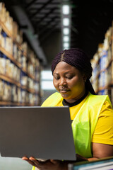 African american woman works in storage room of a large business, space filled with stacked boxes...