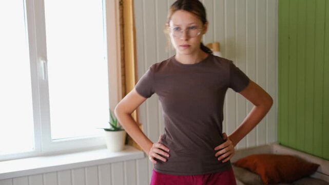 14 years old teenager customized workout, a mix of strength training, flexibility exercises, and cardio at home. Authentic shot. Teen girl exercises with dumbbells. Holistic Health, Mental WellBeing