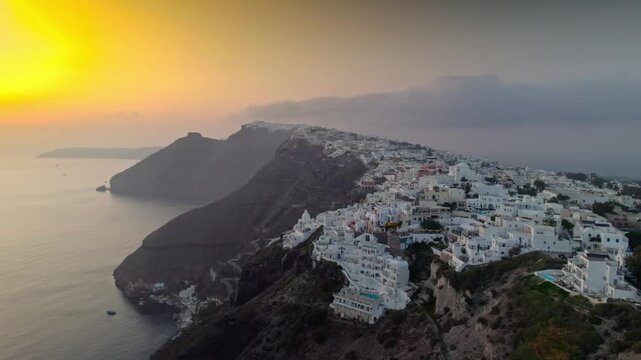 Flying to cliffside buildings over the ocean at sunset 4K