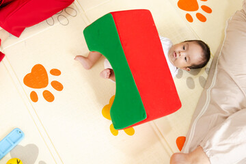  Four-month-old premature baby in physical therapy, lifting foam block as part of motor stimulation, in clinic, child development