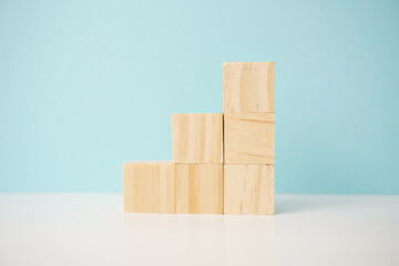Wooden cubes stacked in a stepped arrangement on a blue background, symbolizing growth, development, and stability; for business, health and education concepts.