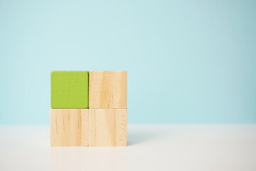 Wooden cubes arranged in a stack against a soft blue background, highlighting minimalistic design...