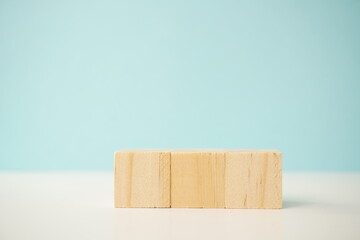 Minimalist display of four natural wooden blocks on light blue and white background, symbolizing...
