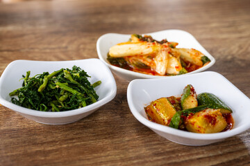 Traditional Korean Side Dishes with Kimchi and Vegetables on Wooden Table