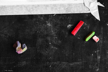 Artistic workspace with red and green pastel sticks and a kneaded eraser on a dark monochrome...