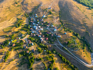 Aerial drone view of a small rural village surrounded by golden fields and greenery in Turkey,...
