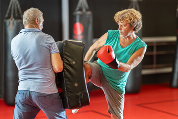 Two men practicing punching during self-defense training. Coach helps