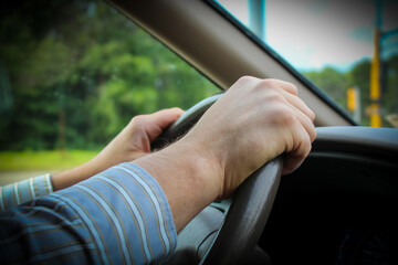 Closeup of a driver in a business shirt with hands on the steering wheel. commuting, going to work,...