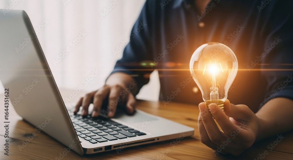 Poster glowing idea person holds illuminated lightbulb while working on laptop.