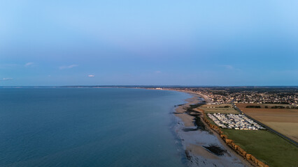 Aerial view of coastal landscape with ocean, beach, and town at dusk.