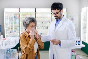 Pharmaceutics, health care concept. Male pharmacist reading list of prescription standing near sick...