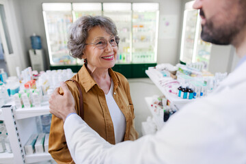 Lovely senior woman buying medications at the drugstore, friendly male pharmacist helping his...