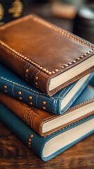 Stack of leather-bound notebooks.  Stacked leather journals in brown and navy blue, featuring decorative stitching and rivets