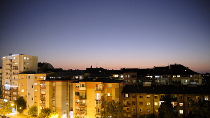 A vast, minimalist landscape of a golden wheat field under a pale sky. A lone water tower stands on the distant horizon, creating a striking visual.