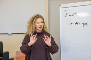 Caucasian female teacher communicates in Russian sign language with students.