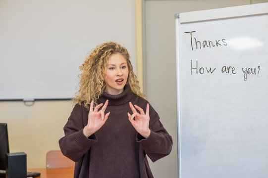 Caucasian female teacher communicates in Russian sign language with students.