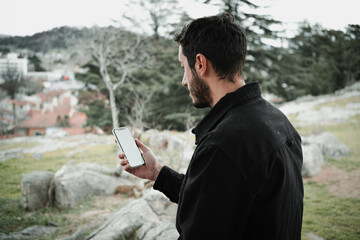 Close-up of a young man sitting in a park and using a smartphone. Copy and paste on cell phone...