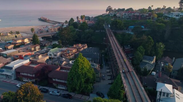 Aerial view of Capitola, California, USA, featuring the beach, pier, and a couple walking on the trestle bridge. The image captures the town's coastal charm.