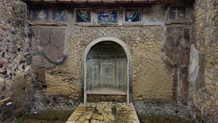Herculaneum, Italy - 9 January 2025. A decorative arched alcove with faint painted details and...