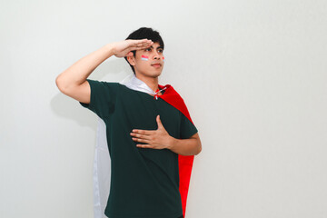 Indonesian man saluting while holding the national flag on a white isolated background, perfect for...