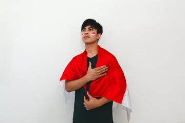 Indonesian man saluting while holding the national flag on a white isolated background, perfect for...