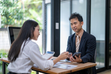 Obraz premium Business colleagues using calculator and mobile phone while working together in office