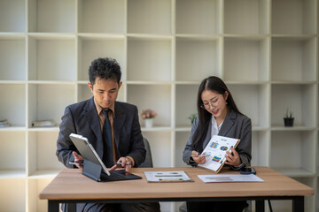 Business people working and discussing using tablet and documents with charts and graphs in office meeting