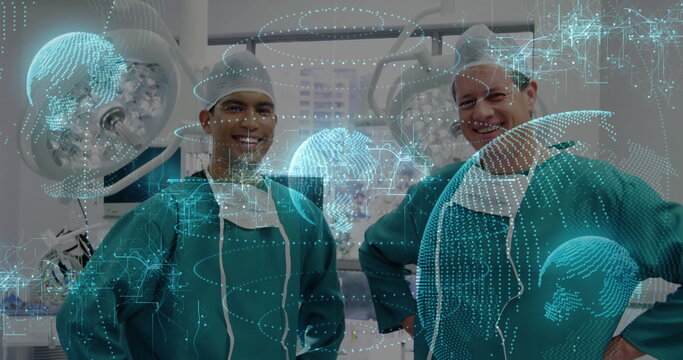 Standing two surgeons in green gowns checking monitors in operating room, with holographic globes