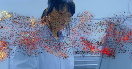 Examining holographic red and gold particle projection, researcher in lab coat in lab with laptop