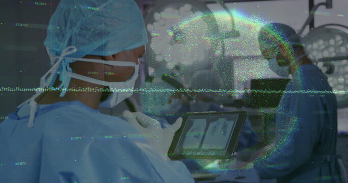 Examining surgeon in blue scrubs holding tablet at operating room, monitors and lights, copy space
