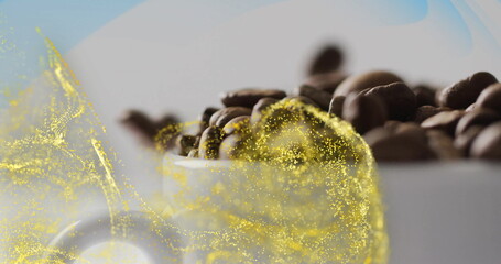Showcasing white ceramic cup holding roasted coffee beans in studio, with golden particle swirl