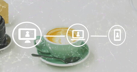 Displaying green coffee cup resting on saucer on white desk, with metal spoon, lens, network icons
