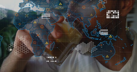 Raising mature man drinking from glass tumbler in room with foliage view, map overlay, copy space