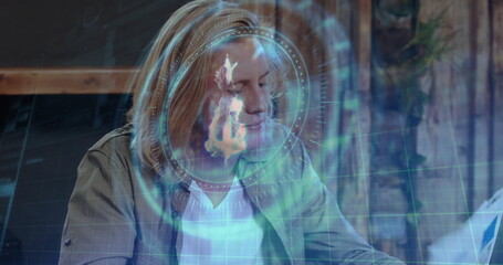 Analyzing man in overshirt reviewing document at studio desk, with floating holographic interface