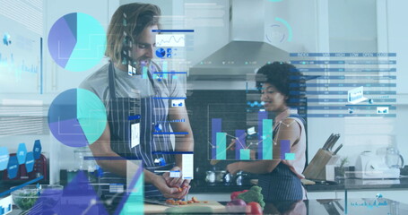 Couple in aprons chopping carrots and consulting smartphone at kitchen island with floating data