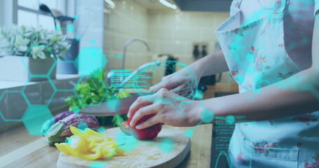 Woman wearing floral apron chopping red bell pepper in kitchen, with cutting board and AR overlay