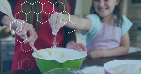 Mixing mother and daughter in aprons stirring batter on kitchen counter with green bowl and flour